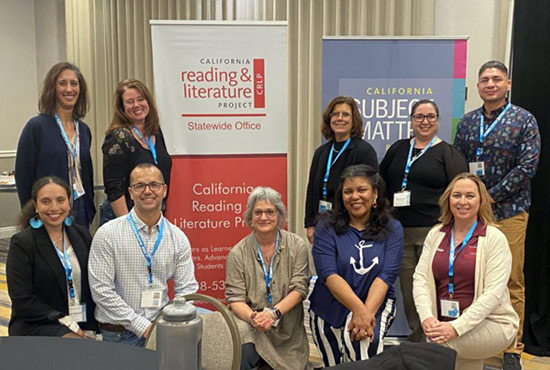 A group of people posing in front of conference signage.