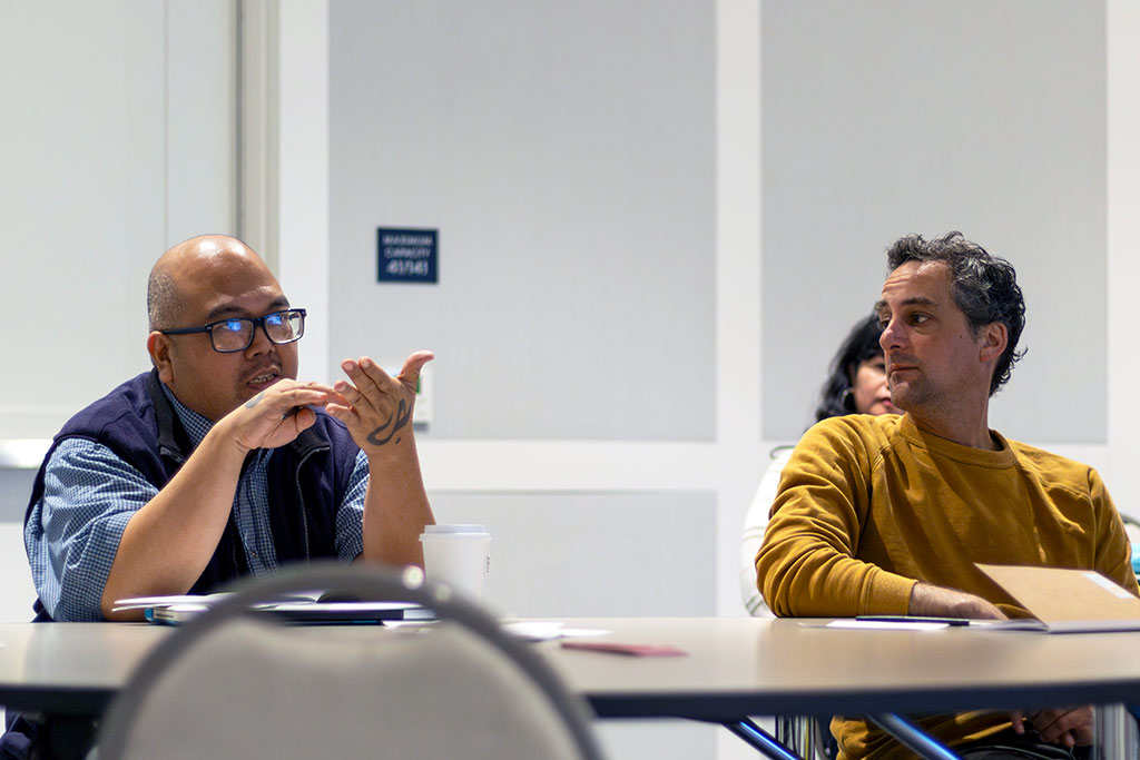 Two people sitting at a table, participating in a group discussion during a CRLP learning event
