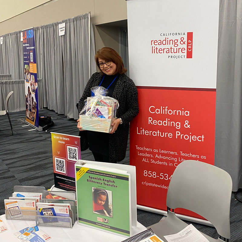 A woman posing with a basket at the CRLP materials table during an event.